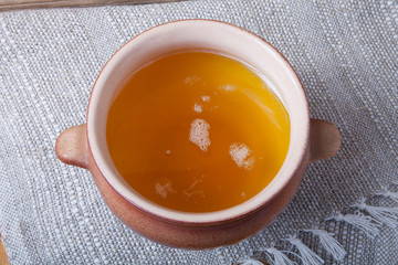 Clay pot with ghee and spoon on linen napkin. Rustic still life.