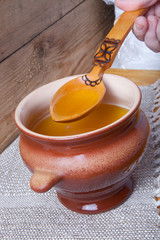 Clay pot with ghee and spoon on linen napkin. Rustic still life.