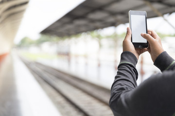 man holding smartphone at train station