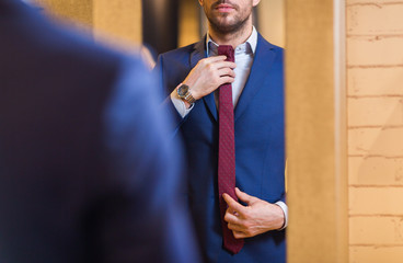 close up of man trying tie on at mirror