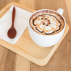 A cup of coffee with flower latte art on top.