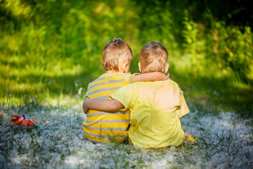 Two little boys friends hug each other in summer  garden. Brothe