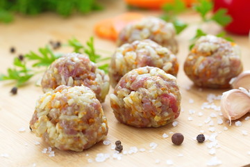 Raw meatballs on a chopping board and ingredients