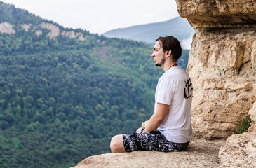 Naklejka premium Man sitting on top of a mountain and enjoying a valley view