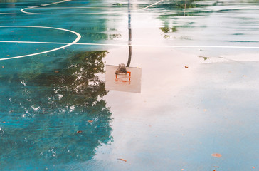 Basketball court after rain. Basketball half-court line. Outdoor court wet with rain. Court with reflective water. Tree and sun reflection on water. Abstract art. Minimal design. Abstract design. - 117284088