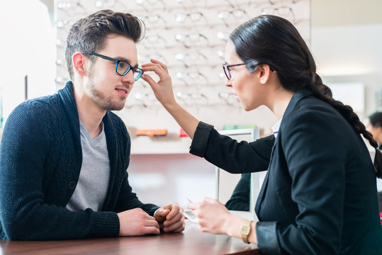 Mann beim Optiker lässt sich von Verkäuferin beraten beim Kauf einer Brille