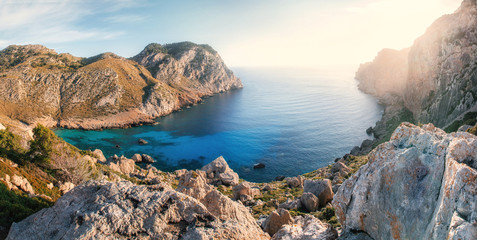 Fototapeta na wymiar View of one of the most beautiful bays of Cap de Formentor at sunrise with azure water, wild beach, mountains and stones, Mallorca, Spain