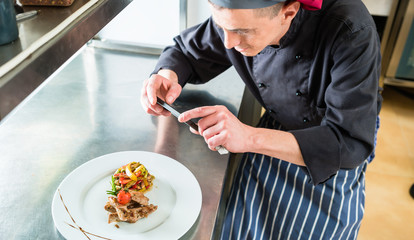Koch fotografiert das von ihm gekochte Essen mit Telefon