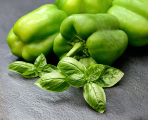 fresh green bell peppers and basil on a dark background