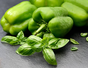 fresh green bell peppers and basil on a dark background