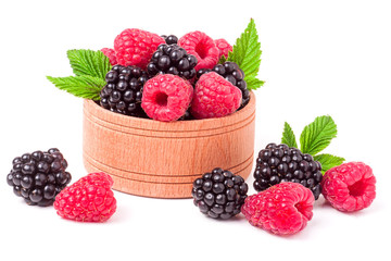 blackberries and raspberries spilled from wooden bowl isolated on white background