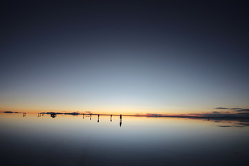 ウユニ塩湖の鏡張りと夕日を眺める人々