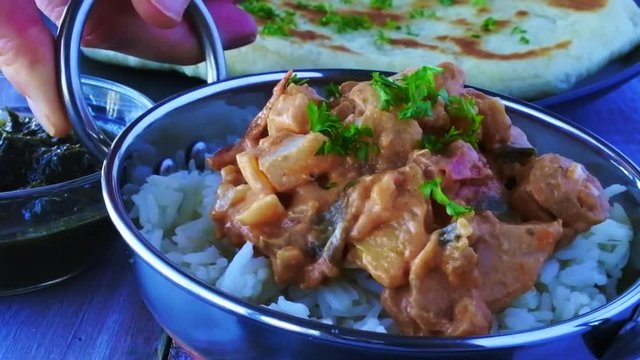 Indian woman serve a traditional Indian butter chicken curry with basmati rice. Food background.