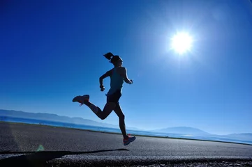 Fotobehang  young fitness woman runner running on sunrise seaside trail © lzf