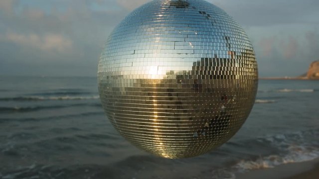 discoball spins during sunrise on the beach