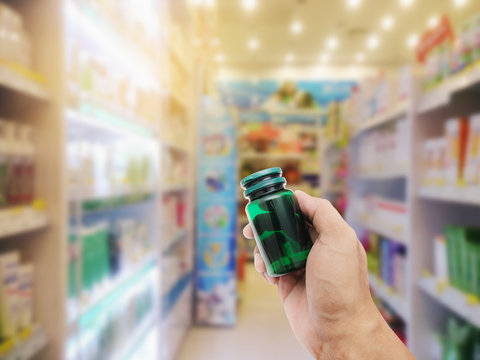 Hand with plastic pill bottle on pharmacy store
