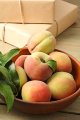 Peaches in the bowl near the gifts on wooden background
