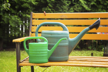 Garden watering cans for watering of plants in a garden on a bench.