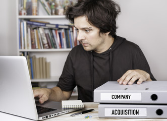 Company and Acquisition - two folders on office desk. Man workin