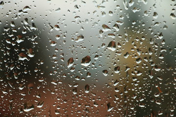 Rain drops on window with house and church in background