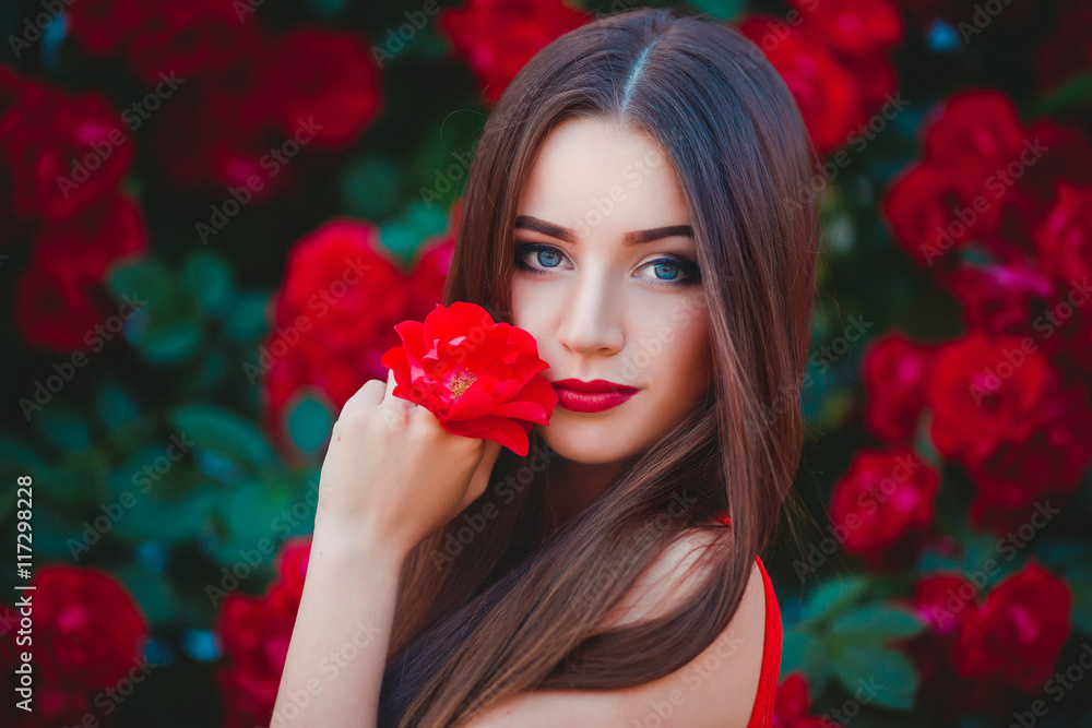 Wall mural beautiful portrait of sensual brunette young woman close to red roses