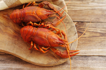 Boiled crawfishes on a wooden board on a wooden background, close up
