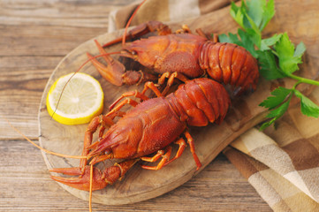 Boiled crawfishes on a wooden board on a wooden background, close up
