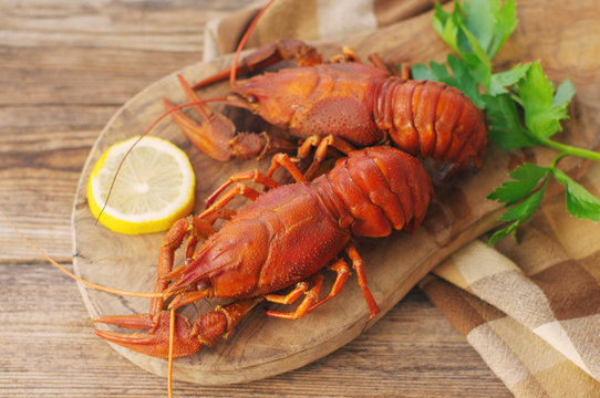 Boiled crawfishes on a wooden board on a wooden background, close up
