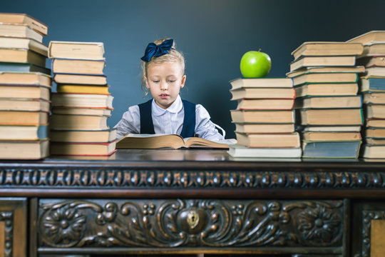 Smart school girl reading a book at library