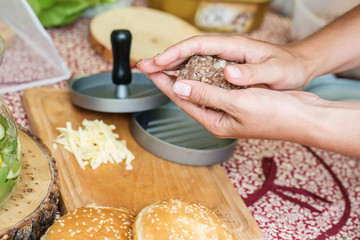 woman is preparing hamburgers, making hamburger, photography with rolls, raw meat, cheese on table