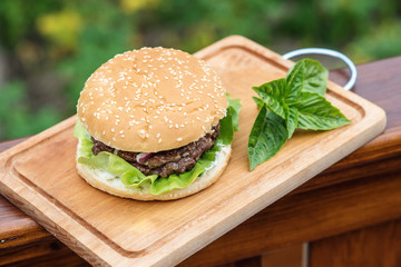 homemade beef or pork hamburger with vegetable and basil leaf on chopping board in garden, food photoraphy