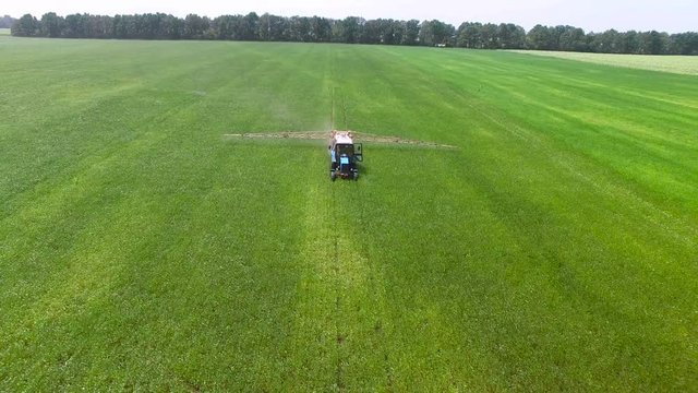 Tractor in a field spray the plants with pesticides. aerial survey