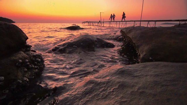 Rock beach on evenning with old wood bridge and travelers 
