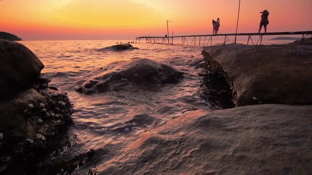 Rock beach on evenning with old wood bridge and travelers 
