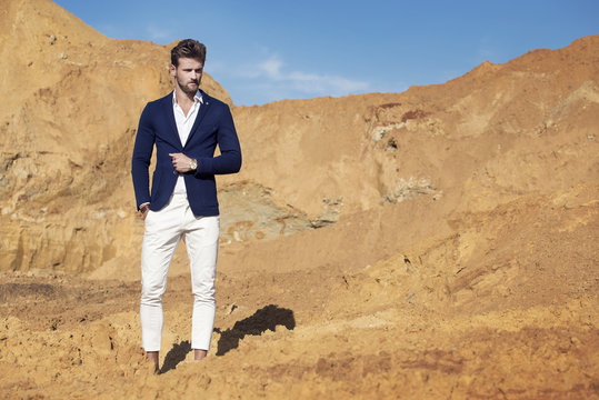 Handsome man elegantly dressed walking the desert