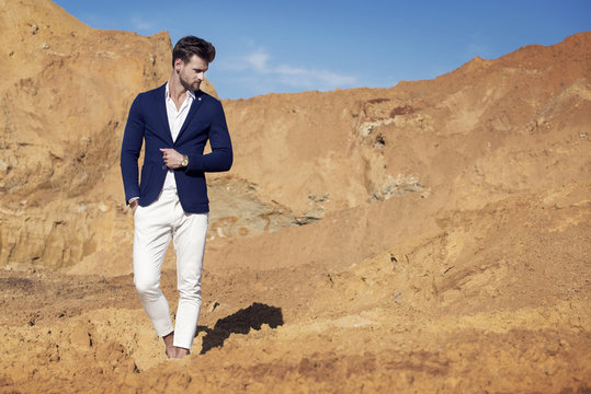 Handsome man elegantly dressed walking the desert