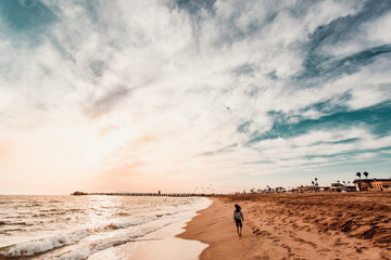 Person walking at waters edge on beach