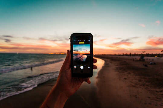 Person taking photo of beach on smartphone