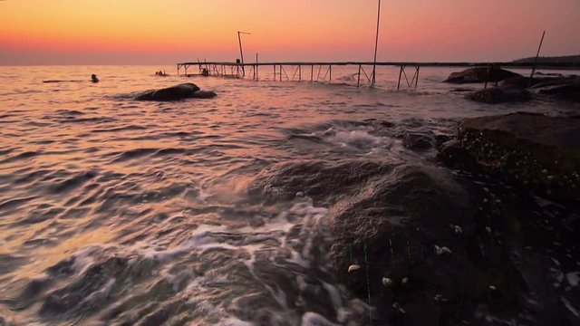 Rock beach on evenning with old wood bridge and travelers 

