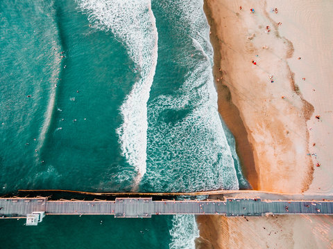 Pier in sea with surf at waters edge