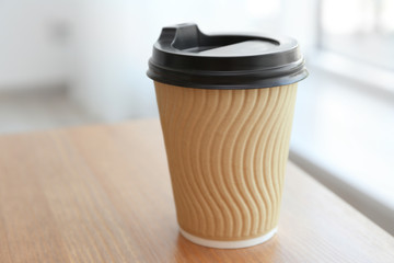 Paper cup of coffee on light background