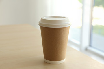 Paper cup of coffee on blurred background