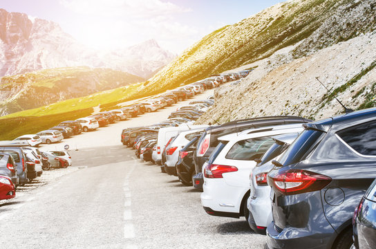 Cars in a parking lot in a middle of mountains. Vehicles on a beautiful sunshine. Transportation background