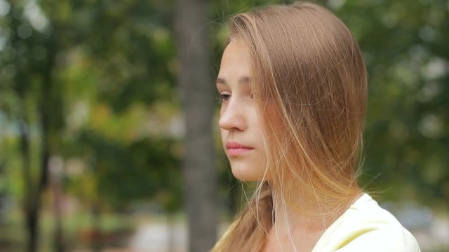 Portrait of beautiful sad teen girl with hand in hair looking away outdoor