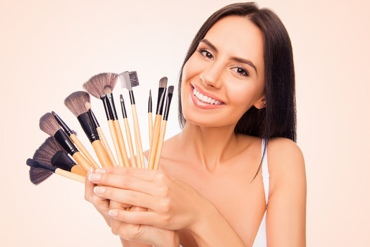 Portrait of young smiling happy woman holding makeup brushes