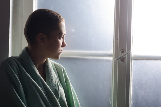 Young depressed cancer patient in front of hospital window