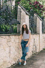 Fototapeta na wymiar Beautiful girl in stylish jeans and white hat walking on the streets and happy.