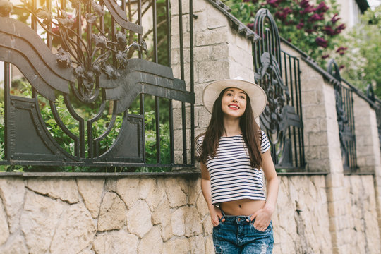Beautiful girl in stylish jeans and white hat walking on the streets and happy.