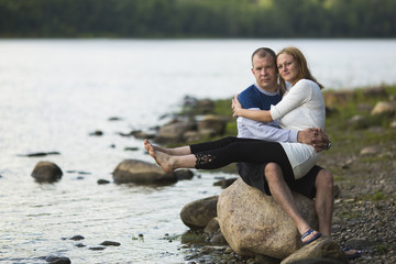 Young couple sitting on a rock by the river. Honeymoon.