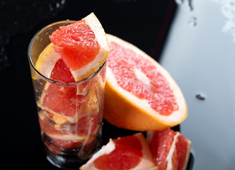 Half grapefruit citrus fruit on black background with water